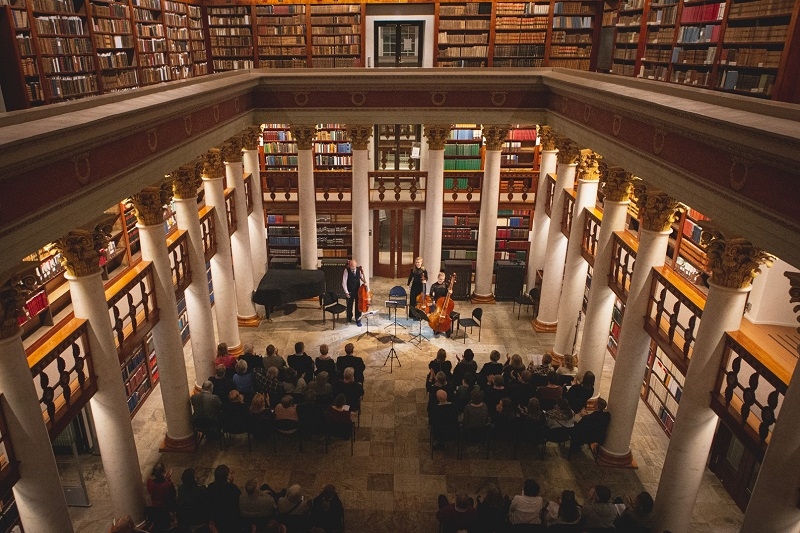 Yleisö kuuntelemassa musiikkiesitystä vanhassa kirjastosalissa